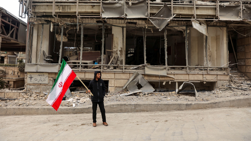 ইসরায়েল-যুক্তরাষ্ট্রের বিমানহামলায় তেহরানের গান্ধী হোটেল হাসপাতাল বিধ্বস্ত হওয়ার পর সেখানে এক ব্যক্তি ইরানের পতাকা হাতে দাঁড়িয়ে পড়েন। ছবি: রয়টার্স