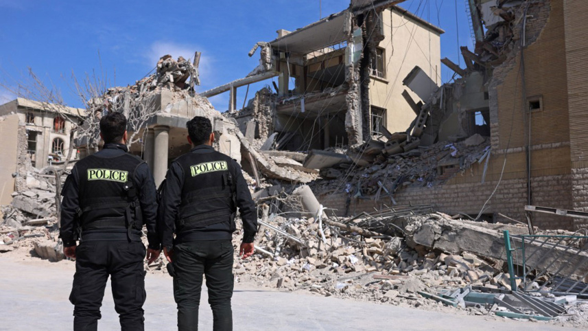 Policemen look at the destroyed buildings following airstrikes in central Tehran