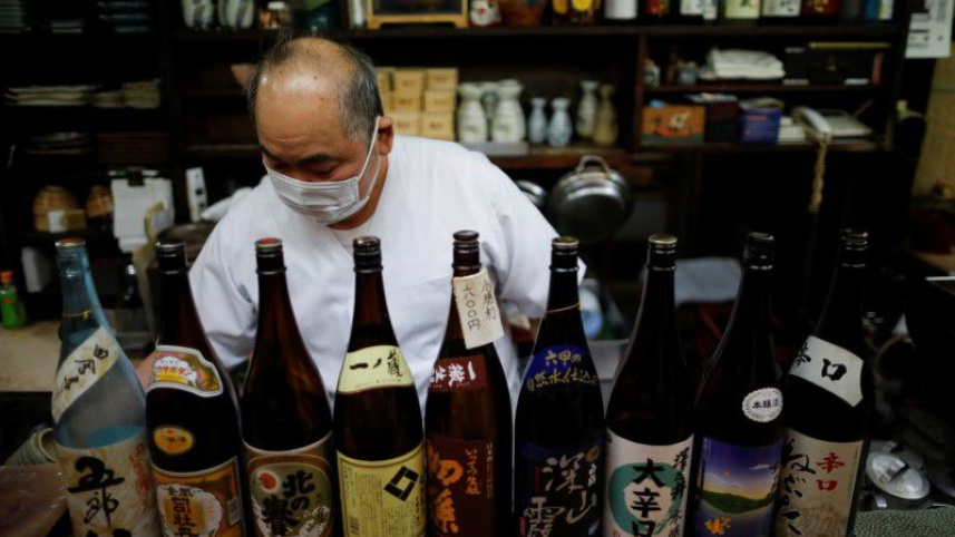 রেস্তোরাঁ বন্ধের আগে মদের বোতল সাজাচ্ছেন জাপানের এক রেস্তোরাঁ মালিক। ফাইল ছবি: রয়টার্স