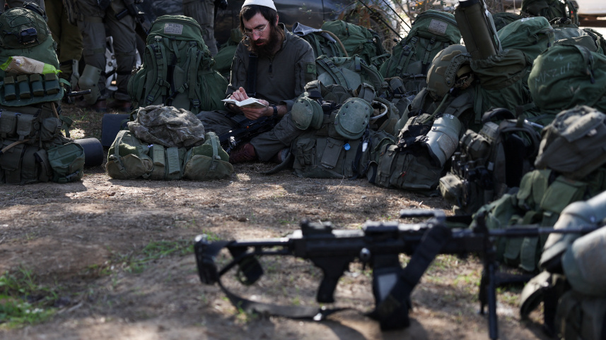 যুদ্ধের ফাঁকে বই পড়ছেন এক ইসরায়েলি সেনা। ছবি: রয়টার্স
