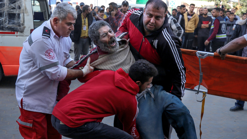 আল মাঘাজি শরণার্থী শিবিরে হামলার পর আহতদের হাসপাতালে নেওয়া হচ্ছে। ফাইল ছবি: এএফপি (১১ ডিসেম্বর)