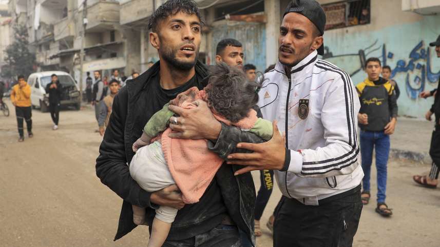 রাফাহ অঞ্চলে ইসরায়েলি হামলায় আহত শিশুকে বহন করছেন এক ব্যক্তি। ছবি: এএফপি (১৪ ডিসেম্বর) 