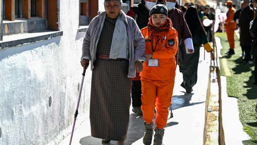 এক বয়স্ক ভোটারকে সাহায্য করছেন পুলিশ কর্মকর্তা। ছবি: এএফপি