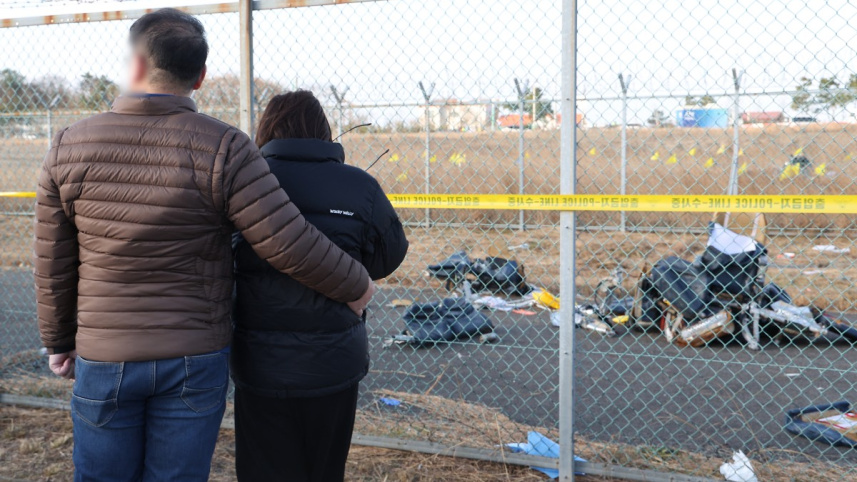 বিধ্বস্ত উড়োজাহাজ পর্যবেক্ষণ করছেন নিহতদের আত্মীয়রা। ছবি: এএফপি