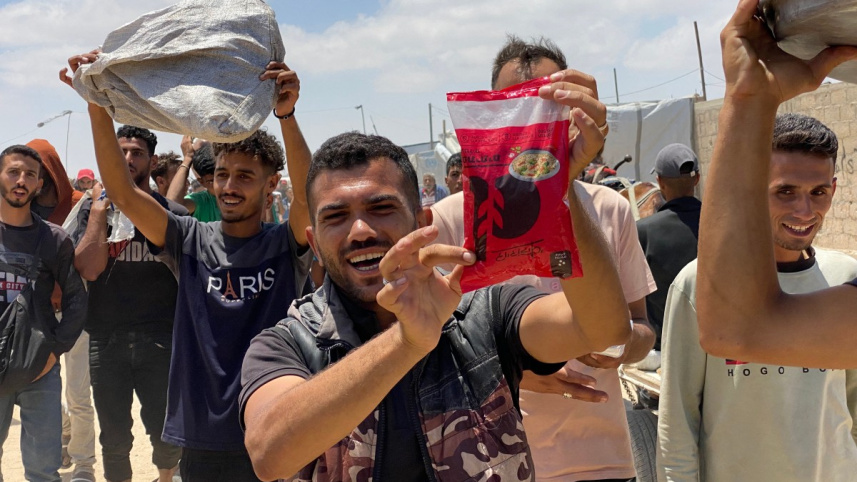 ত্রাণকেন্দ্র থেকে ত্রাণ পেয়ে উল্লাস প্রকাশ করছেন ফিলিস্তিনিরা। ছবি: এএফপি