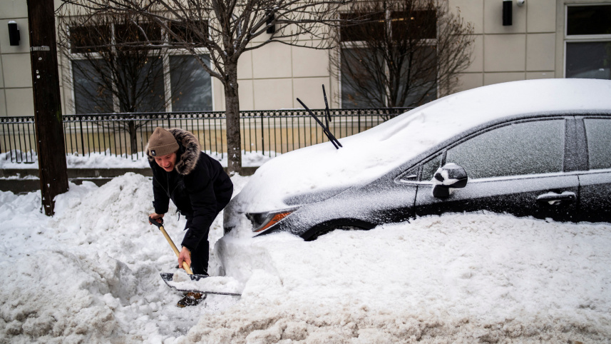 বাড়ির সামনে থেকে বরফ পরিষ্কার করার চেষ্টা করছেন এক ব্যক্তি। ছবি: রয়টার্স