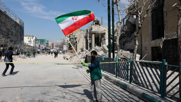 ইসরায়েলি হামলার পর তেহরানের রাস্তায় পতাকা ওড়াচ্ছেন এক ইরানি। ছবি: রয়টার্স