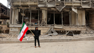 ইসরায়েল-যুক্তরাষ্ট্রের বিমানহামলায় তেহরানের গান্ধী হোটেল হাসপাতাল বিধ্বস্ত হওয়ার পর সেখানে এক ব্যক্তি ইরানের পতাকা হাতে দাঁড়িয়ে পড়েন। ছবি: রয়টার্স