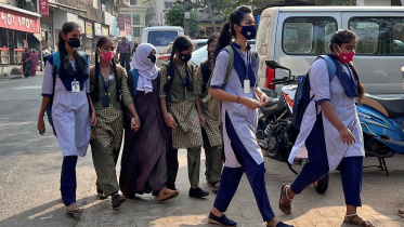 কর্নাটকের একটি স্কুলে হিজাব পরা এক শিক্ষার্থী তার বান্ধবীদের হাত ধরে শ্রেণীকক্ষে প্রবেশ করছেন। ফাইল ছবি: রয়টার্স