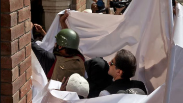 ইমরান ও তার স্ত্রী আদালতে উপস্থিত হওয়ার সময় পুলিশ তাদের চারপাশে সাদা চাদর উঁচিয়ে ধরে। ফাইল ছবি: রয়টার্স