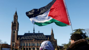 আইসিজে ভবনের সামনে ফিলিস্তিনি পতাকা ওড়াচ্ছেন এক বিক্ষোভকারী। ফাইল ছবি: রয়টার্স