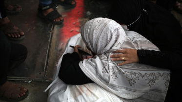 নিহত ফিলিস্তিনির মরদেহের সামনে শোক প্রকাশ করছেন এক নারী। ছবি: এএফপি