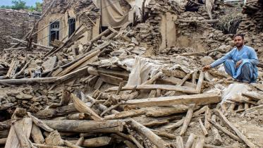 ভূমিকম্পে ধ্বংস হয়ে যাওয়া বাড়ির ভেতর বসে আছেন এক আফগান নাগরিক। ছবি: এএফপি