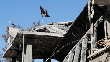 সিরিয়ার রাক্কা শহরের ক্লক স্কোয়ারের কাছে ধ্বংসপ্রাপ্ত বাড়ির ছাদে আইএসের পতাকা উড়তে দেখা যাচ্ছে। ফাইল ছবি: রয়টার্স (১৮ অক্টোবর, ২০১৭)