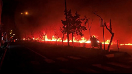 তেহরানের তেলের ডিপোতে ইসরায়েলি বিমান হামলার পর বড় আকারে আগুন ছড়িয়ে পড়ে। এই নারকীয় পরিস্থিতির মধ্যেই এক ব্যক্তি বাইক ছুটিয়েছেন সড়কে। ছবি: এএফপি 