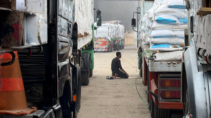 রাফা সীমান্তে সারি সারি ত্রাণবাহী ট্রাকের মাঝে নামাজ আদায় করছেন এক মিশরীয় ব্যক্তি। ছবি: 